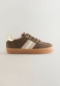 Hnědé semišové tenisky s růžovým a zlatým pleteným pruhem, kulatou špičkou a gumovou podrážkou. Obsahují zlaté detaily a tkaničky.