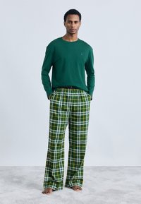 Πράσινο πουκάμισο με μακριά μανίκια και πράσινες καρό πιτζάμες με κίτρινες και λευκές λεπτομέρειες. Μαλακό ύφασμα, χαλαρή εφαρμογή και ελαστική ζώνη.