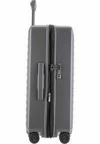 Maleta rígida gris con superficie texturizada, dobles cremalleras, cerradura TSA, asa retráctil y cuatro ruedas negras.