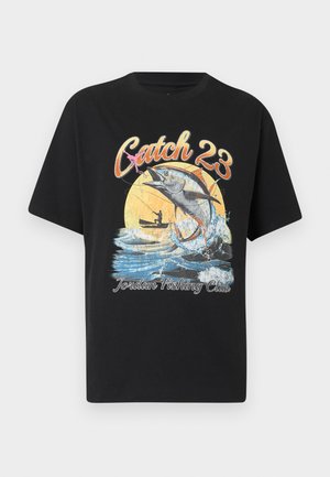 Μαύρο T-shirt με γραφικό μεγάλο ψάρι που πηδά από το νερό, ψαράς σε βάρκα, κείμενο "Catch 23" και "Jordan Fishing Club."