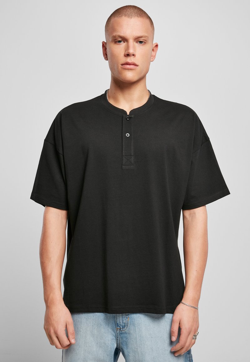 Svart t-skjorte med korte ermer laget av bomull, med rund hals, to-knapps knappestolpe og en avslappet passform. Strukturert stoff, minimalistisk design.