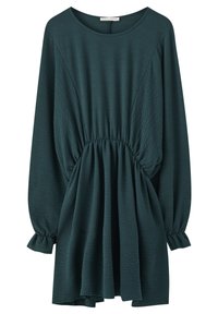 Robe verte texturée avec des manches longues, taille froncée et jupe évasée. Dotée d'un décolleté rond et de poignets élastiques.