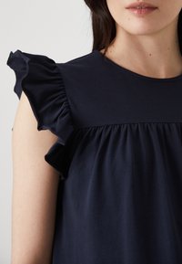 Ναυτικό μπλε φόρεμα με ρυάκια στα μανίκια, φτιαγμένο από μαλακό ύφασμα. Διαθέτει στρογγυλή λαιμόκοψη και συγκεντρωμένο σχέδιο κάτω από το στήθος.