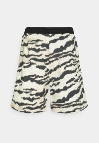 Shorts à motif rayures de tigre en noir et blanc avec une ceinture élastique noire, présentés à plat sur un fond uni.
