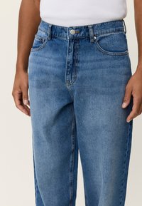 Φως γαλάζια τζιν τζιν με ψηλή μέση, σχέδιο με ίσια πόδια, πεντακάρπια στυλ και κλείσιμο με ασημί κουμπί. Ήπια ξεθωριασμένη υφή.