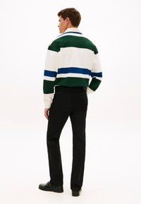 Λευκό και πράσινο ριγέ πουλόβερ με μπλε λεπτομέρειες, σχεδιασμός cropped, συνδυασμένο με μαύρο παντελόνι και μαύρα παπούτσια, λεία υφή, casual στυλ.