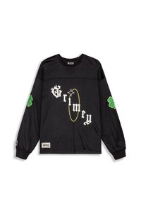 Camisa de manga larga negra con textura de malla, con el texto blanco "Grimey" y un acento en círculo amarillo. Parche de trébol verde en las mangas.