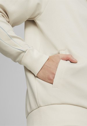 Licht beige sweatshirt van gestructureerde stof, met een zijzak en een blauwe accentnaad langs de mouw. Zacht, ontspannen pasvorm.