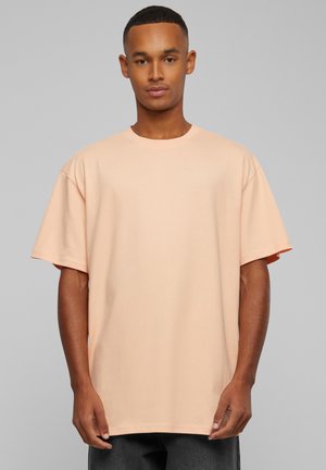 Perzikgekleurde katoenen T-shirt met een comfortabele pasvorm, korte mouwen en een klassieke ronde hals. Glad van textuur, minimale details.