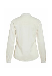 Camicetta a maniche lunghe in tessuto color crema chiaro, con colletto, polsini abbottonati e una spalla dritta senza motivi prominenti.