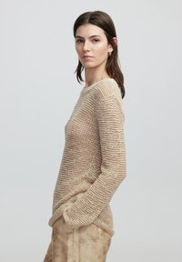 Strickpullover in Beige mit strukturiertem Muster, langen Ärmeln und runder Ausschnitt, ausgestattet mit Seitentaschen und einem lässigen Schnitt.