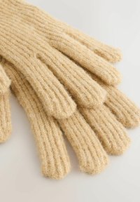 Strikkede uldhandsker i en lysebeige farve. Har ribbet tekstur og fem fingre med afrundede spidser. Blødt og varmt udseende.