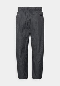 Svarta och vita rutiga byxor med elastisk midja och bakficka, med en rak ben-design och en mjuk tygtextur.