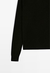Maglione nero a maglia con maniche lunghe, polsini e orlo a coste, caratterizzato da una texture liscia e un design minimalista, senza loghi né decorazioni.
