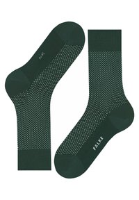 Dunkelgrüne Socken mit einem strukturierten Muster aus kleinen weißen Punkten, ausgestattet mit einem gerippten Bund und einem verstärkten Fersenbereich. Die Marke ist auf der Sohle sichtbar.