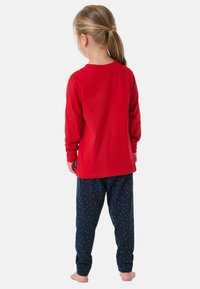 Rotes Langarmoberteil kombiniert mit dunkelblauen Schlafanzughosen, die mit kleinen, mehrfarbigen Punkten verziert sind, aus weichem Baumwollmaterial gefertigt.