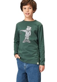 Vihreä pitkähiainen t-paita, joka on valmistettu puuvillasta ja siinä on painettu karhukuva. Yhdistetty sinisiin farkkuihin, jotka näyttävät rentoa istuvuutta ja muotoilua.