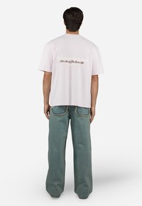 Lichtroze katoenen t-shirt met de tekst "Scent Of Summer" in print op de achterkant. Gekocht in combinatie met losse, vervaagde blauwe spijkerbroek.