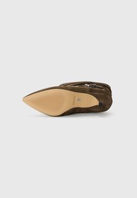 Stivale alla caviglia in suede marrone con punta affusolata, suola testurizzata e dettaglio con cerniera laterale. Presenta una suola in gomma beige con linee antiscivolo.