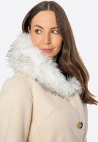 Beżowy płaszcz z puszystym białym kołnierzem z sztucznego futra, z pojedynczym zapięciem na guzik i subtelną teksturowaną tkaniną. Długie, proste rękawy.