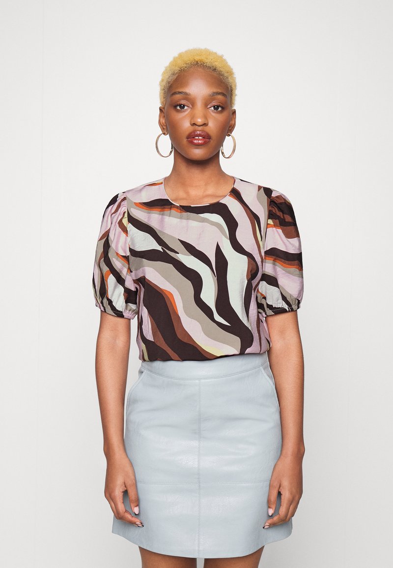 Blusa colorida de manga curta com riscas abstractas em rosa, castanho e laranja, combinada com uma saia mini em couro azul claro. Textura suave, ajuste descontraído.