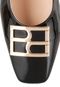 Escarpin en cuir verni noir à bout amande, avec une boucle géométrique dorée à l'avant et une finition lisse et brillante.