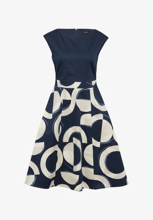 Robe bleu marine avec un corsage ajusté et une jupe évasée ornée d'un motif circulaire crème. Manches courtes et fermeture éclair invisible au dos.