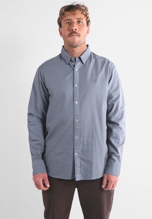 Chemise à manches longues bleu clair en coton, dotée d'un col boutonné, de boutons à l'avant et d'un petit logo brodé sur la poitrine.
