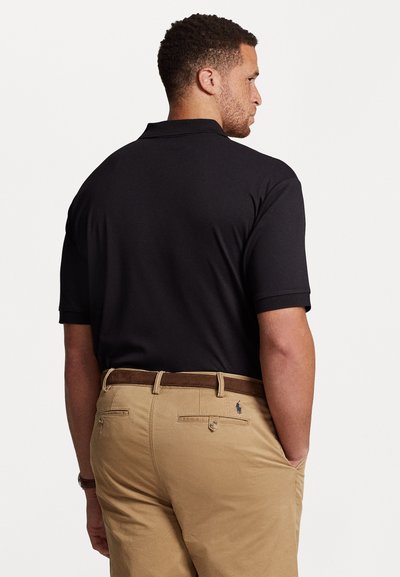 Μαύρο πόλο μπλουζάκι με άνετη εφαρμογή, κοντά μανίκια και γιακά, συνδυασμένο με καφέ παντελόνι και καφέ ζώνη. Λεπτό λογότυπο στο παντελόνι.