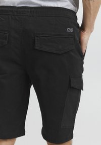 Zwarte cargoshorts van katoen, met meerdere opgestikte zakken en een relaxed fit, met een elastische tailleband voor comfort.