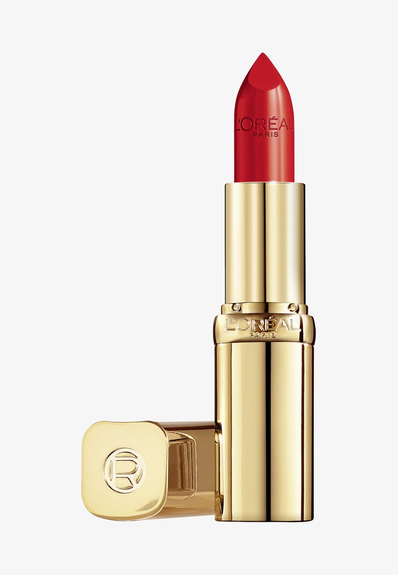 Rode lippenstift in een gouden metalen behuizing met een puntige tip en een gegraveerde merknaam. De dop heeft een cirkelvormig logo. Compacte formaat voor eenvoudige hantering.