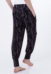 Svarta joggerbyxor med ett grått abstrakt blommönster, mjukt tyg, elastisk midja och smalnande muddar. Sidfickor ingår.