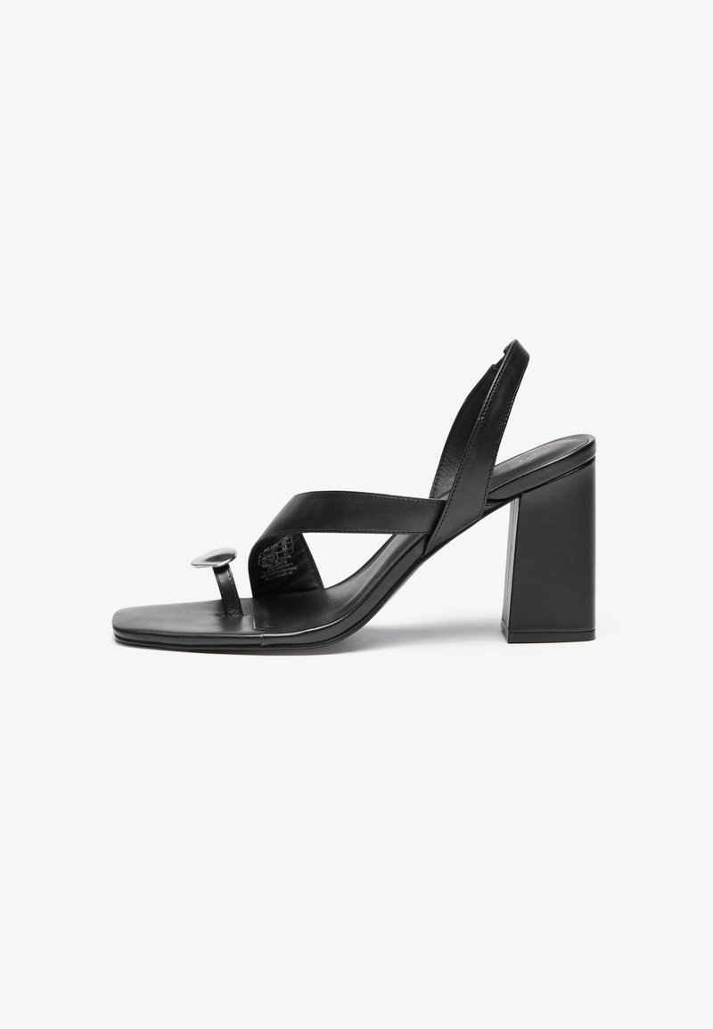 Sorte læder højhælede sandaler med flad sål, der har krydsede stropper, en rund metallisk detalje og en solid blokhælk.