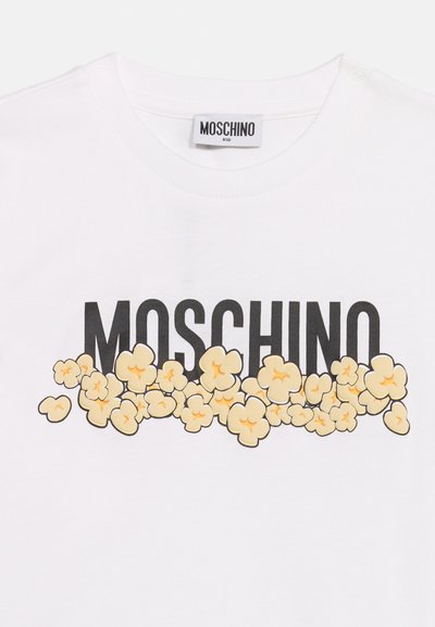 Λευκό παιδικό T-shirt Moschino με μαύρο κείμενο λογότυπου που είναι μερικώς καλυμμένο από διάσπαρτο γραφικό με ποπ κορν στο εμπρός μέρος.