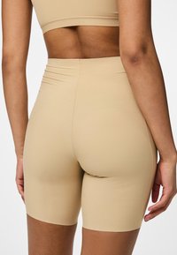Beiga cykelshorts i ett mjukt, stretchigt material. Hög midja med subtila sömnadsdetaljer. Slank passform som slutar vid mitten av låret.