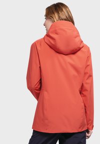Rote wasserdichte Jacke mit figurnahem Schnitt und großer Kapuze. Zu den Merkmalen gehören nahtlose Schulternähte und eine glatte Textur.
