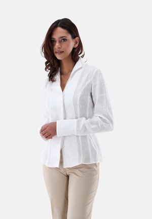 Camicia bianca a maniche lunghe con colletto, caratterizzata da una trama verticale e bottoni lungo la parte anteriore, abbinata a pantaloni beige.