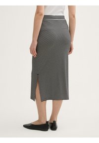 Gonna midi a righe bianche e nere con uno spacco laterale, realizzata in un tessuto leggero. Presenta una vita aderente e una silhouette snella.