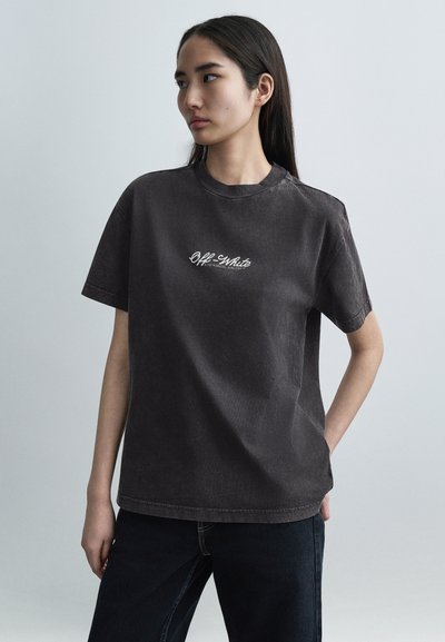 Camiseta de algodón gris oscuro con cuello redondo, mangas cortas y logo bordado en el frente. Corte holgado con textura suave.