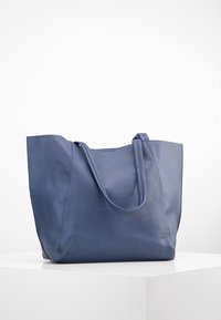 Modrá kožená taška s hladkým povrchem, širokým otvorem a dvěma pevnými uchy. Má minimalistický design bez viditelného kovového příslušenství.