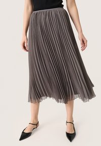 Grijze geplooide midi-rok van lichtgewicht stof met een vloeiende silhouet en zachte, doorschijnende textuur, gecombineerd met zwarte puntige schoenen.