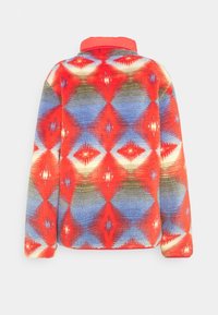 Fleece bunda s živým geometrickým vzorem v červené, modré a zelené barvě, s vysokým límcem a texturovanou tkaninou.