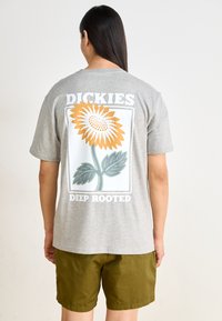 Gray short-sleeve t-shirt featuring a large sunflower graphic in orange and green on the back, with "DICKIES" and "DEEP ROOTED" text.