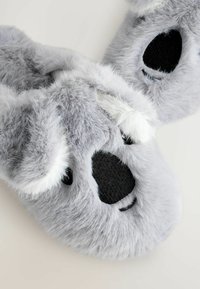 Grå plyssede tøfler formet som koalaer, med blødt pels, rund sort næse og ører, samt sort stof på sålen for kontrast.