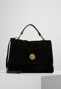 Czarna zamszowa torebka z klapką, złotymi okuciami i odpinanym paskiem na ramię. Na przedzie znajduje się okrągłe logo.