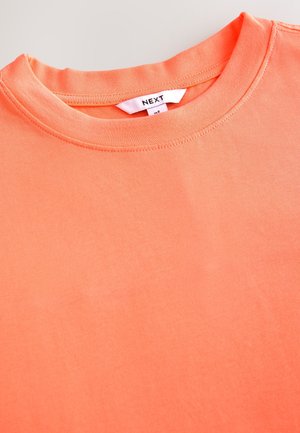 Trumparankovė marškinėliai ryškiai koralų spalvos, pagaminti iš minkštos medvilnės. Turi apvalų kaklo iškirpimą ir siūtinį etiketę su užrašu „NEXT“. Lygi tekstūra.