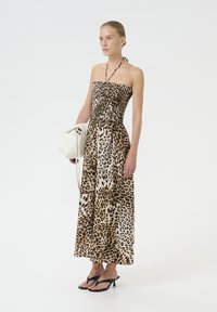 Sleevless leopard print maxikjole med elastisk overdel, flydende stof, sorte flip-flops og en hvid håndtaske. Simpelt, elegant design.