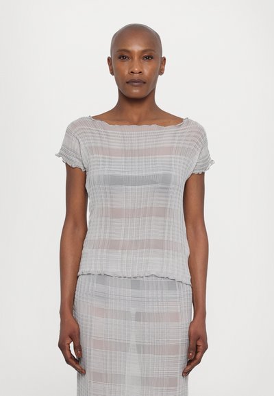Top transparent de culoare gri care prezintă un model cu carouri, cu mâneci scurte și decolteu ondulat. Material moale, ușor, cu o croială fluidă.