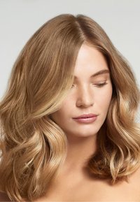 Axellångt vågigt hår i ljusbrunt med blonda slingor. Slät textur och naturlig glans, delat något off-center.