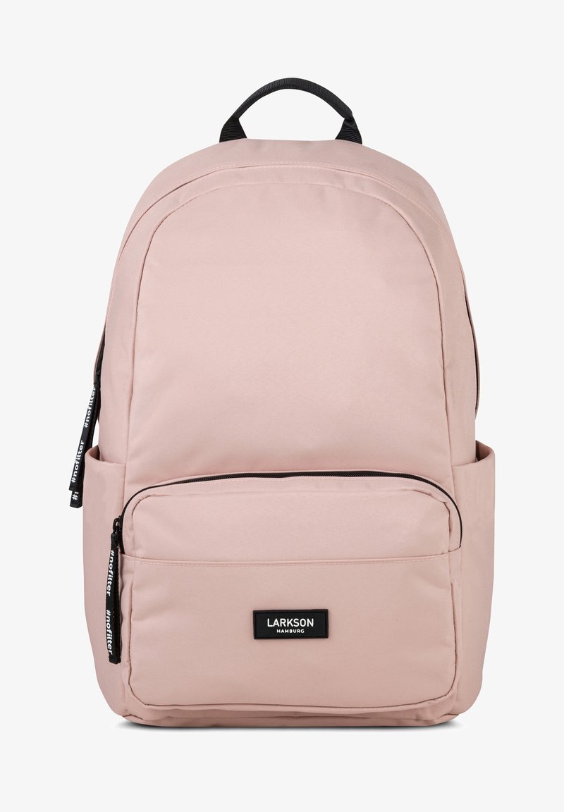 Zaino rosa chiaro a forma arrotondata, realizzato in tessuto. Presenta una tasca frontale con zip e una tasca laterale in rete, etichetta con logo sul davanti.